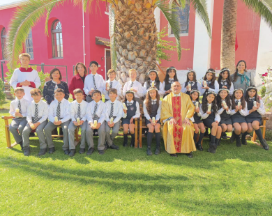 Alumnos de 5to básico, que hicieron la Primera Comunión, junto a sus profesores y el Padre.