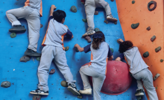 Alumnos subiendo muro de escalada